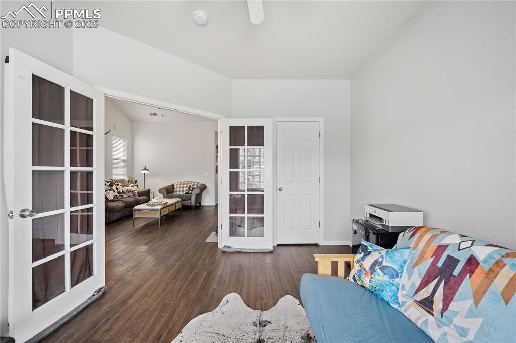 Image 14 of 44: Living area with french doors, wood finished floors, and baseboards
