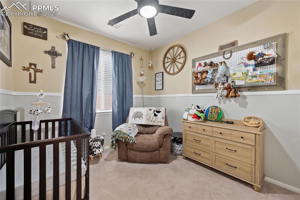 Image 21 of 44: Bedroom featuring light colored carpet, a crib, baseboards, and ceiling fan