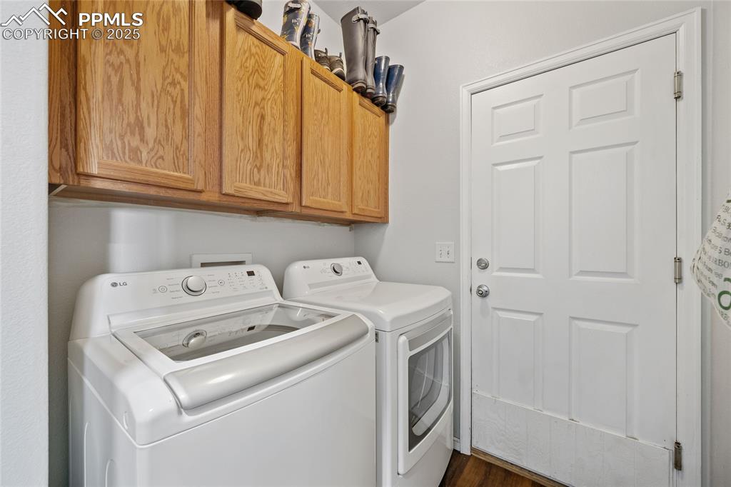 Image 24 of 44: Laundry area with cabinet space, independent washer and dryer, and dark woo