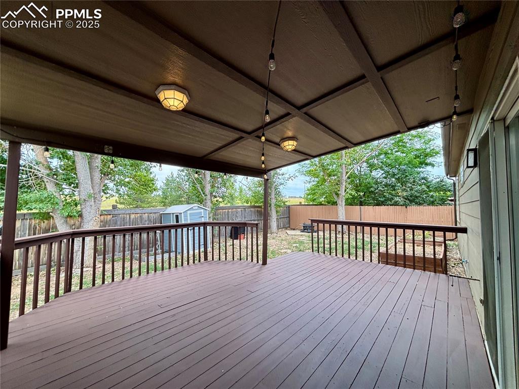 Image 25 of 44: Wooden deck featuring a storage shed and a fenced backyard