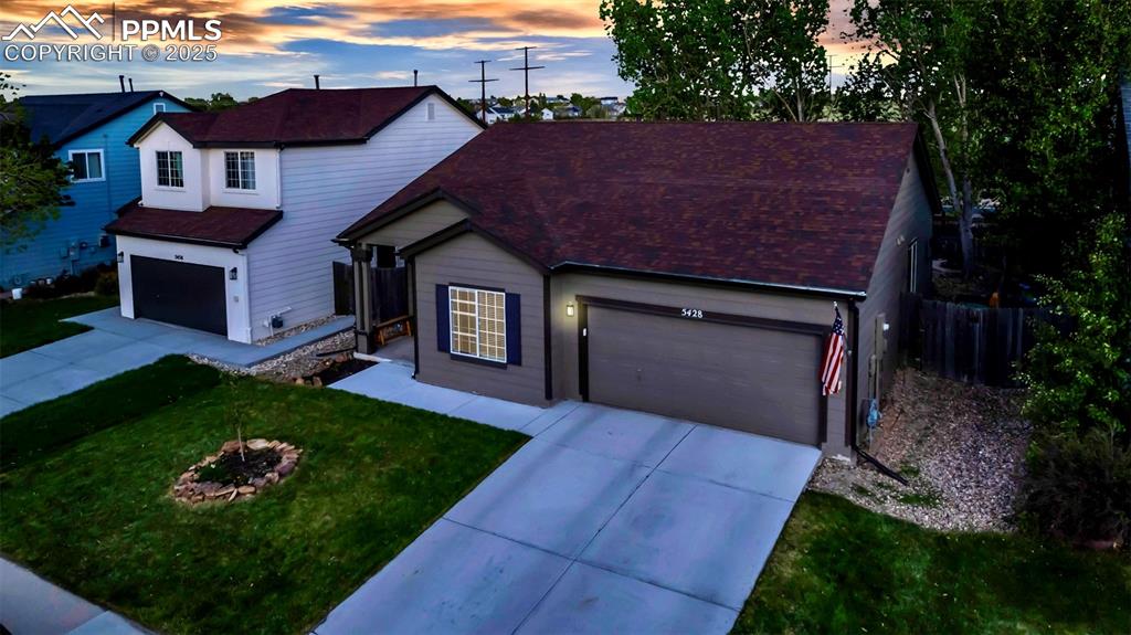 Image 30 of 44: Traditional home featuring an attached garage, driveway, and roof with shin