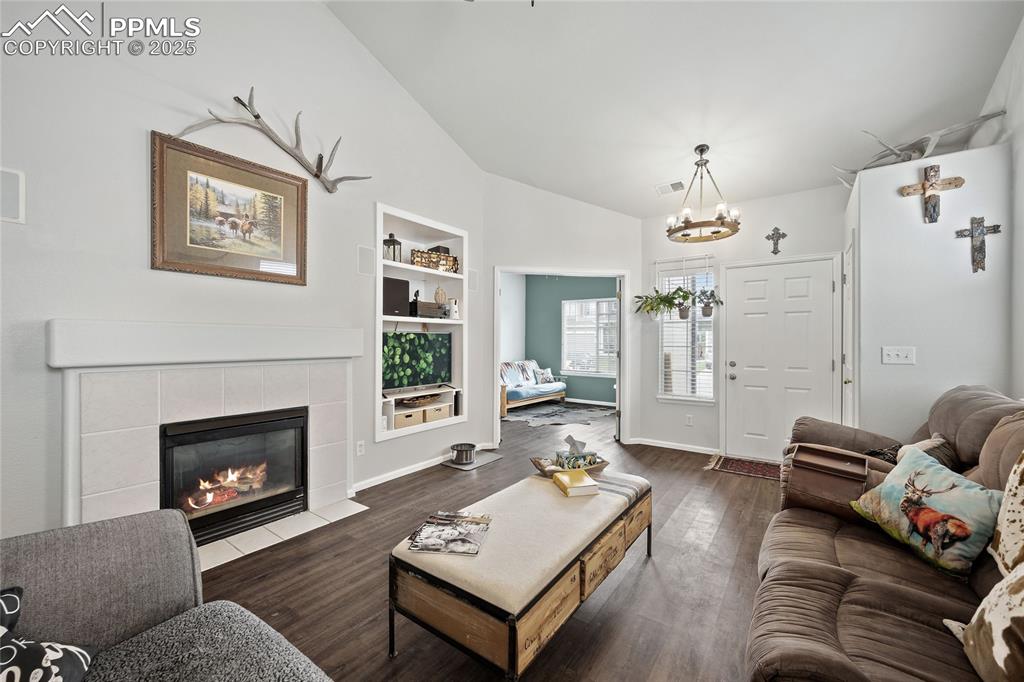 Image 7 of 44: Living area featuring lofted ceiling, a chandelier, built in shelves, wood 