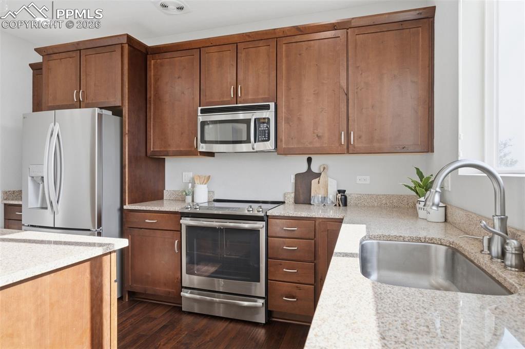 Image 15 of 49: Kitchen featuring wood-finish cabinetry, stainless steel appliances, granit