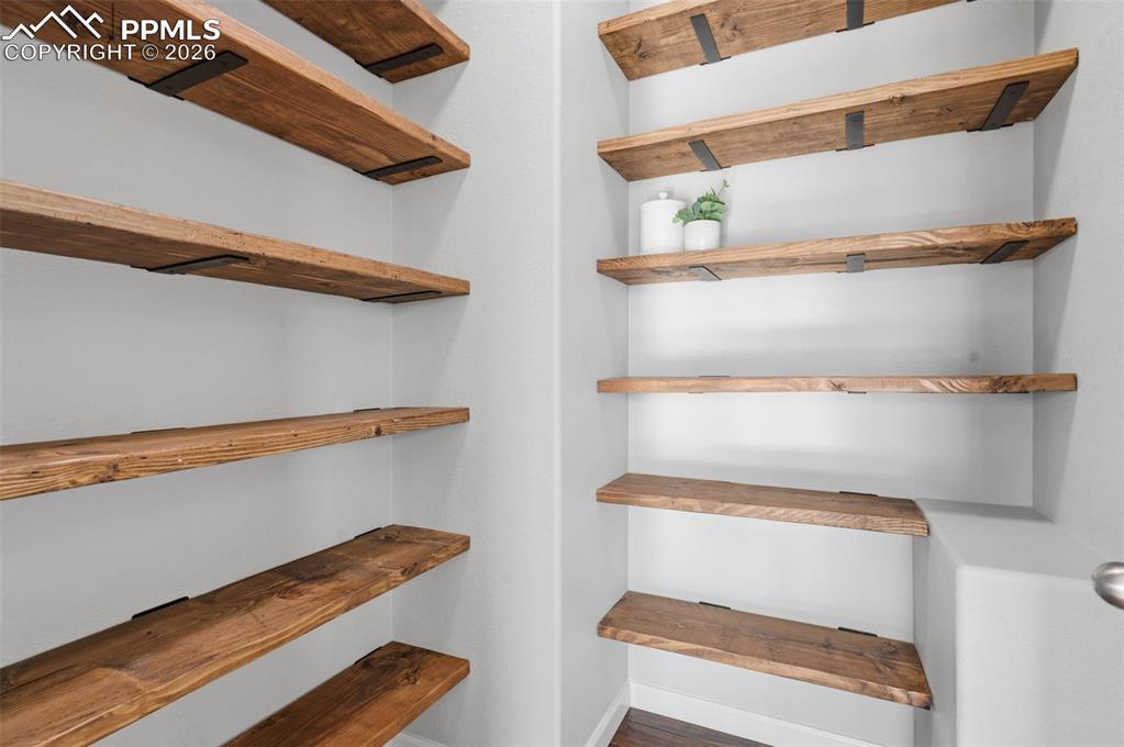Image 16 of 49: Built-in open shelving featuring natural wood planks with black metal suppo