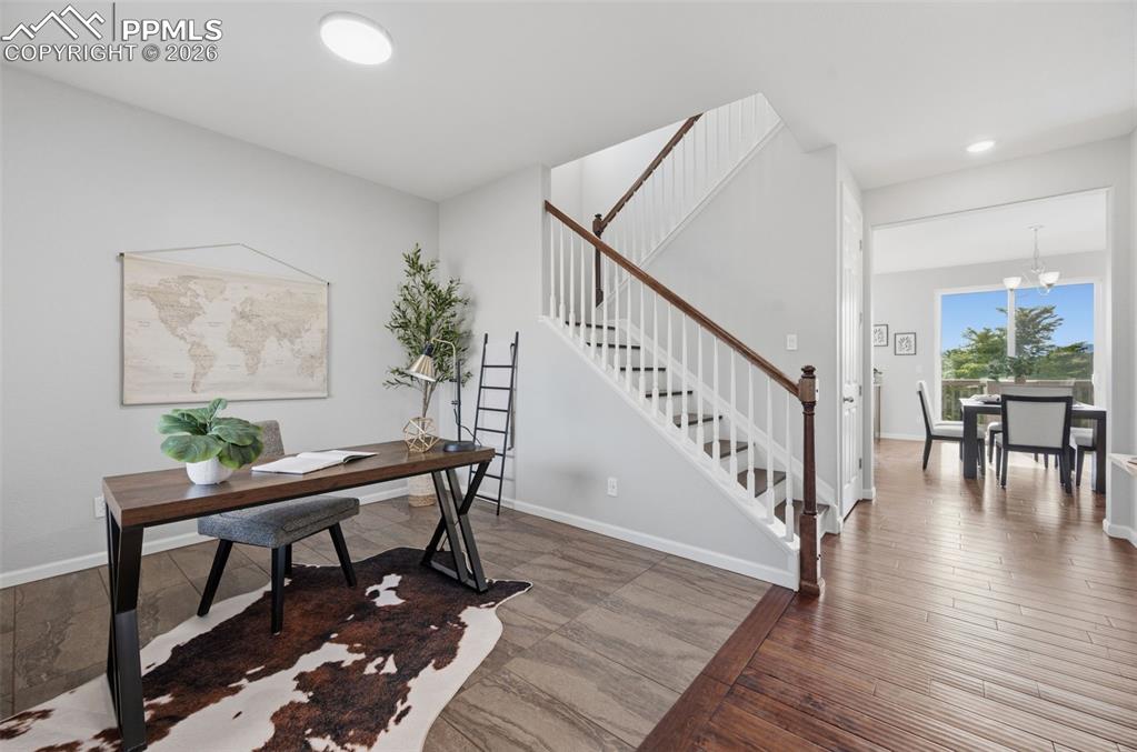 Image 2 of 49: Entryway featuring a wood-finish staircase with white balusters and a dark 