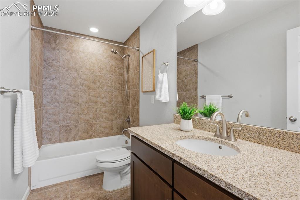 Image 28 of 49: Bathroom featuring a built-in tub with tile surround, a dark wood-finish va