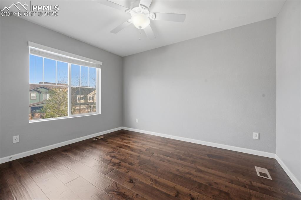 Image 31 of 49: Spacious room featuring wood-finish flooring, a large window, light gray wa