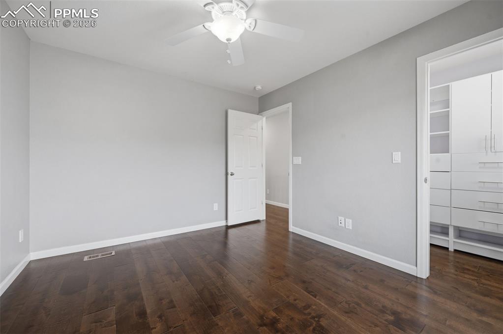 Image 32 of 49: Spacious room featuring dark wood-finish flooring, light grey painted walls