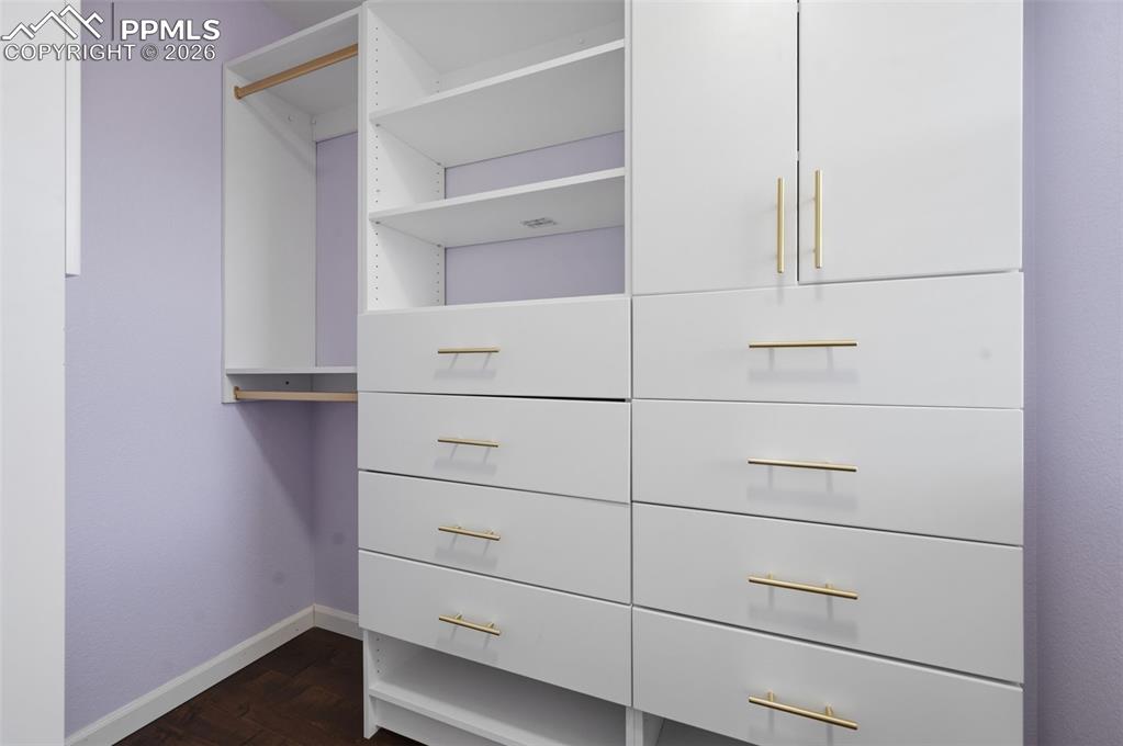 Image 33 of 49: Custom closet system featuring white cabinetry, gold-tone hardware, multipl