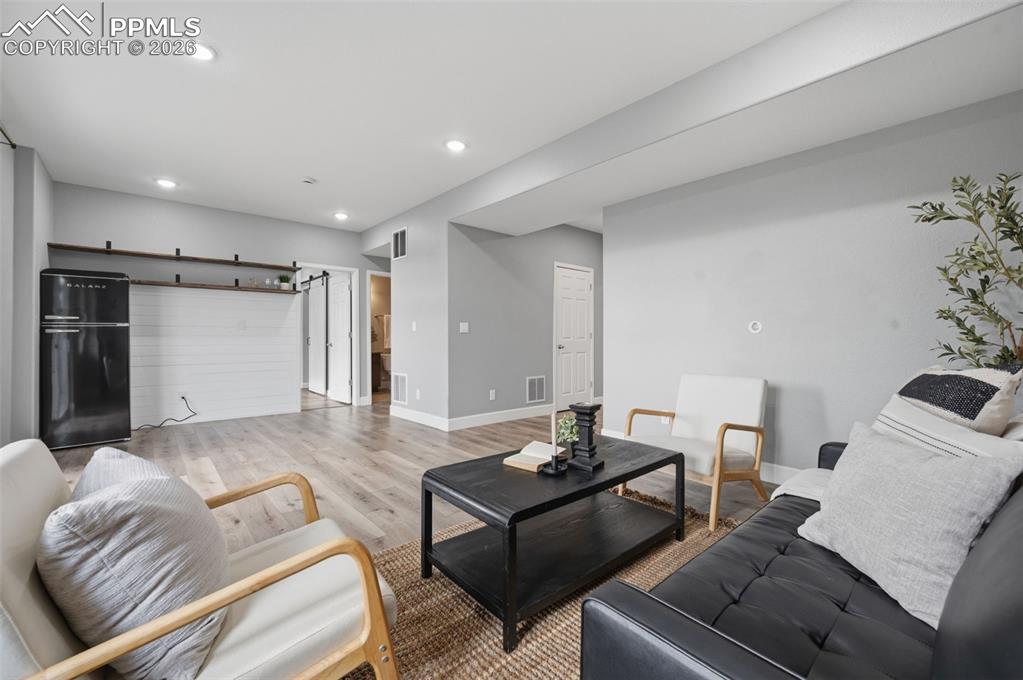 Image 35 of 49: Spacious living area featuring light wood-finish flooring, recessed lightin