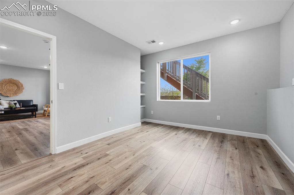 Image 37 of 49: Spacious room featuring light wood-finish flooring, recessed lighting, and 