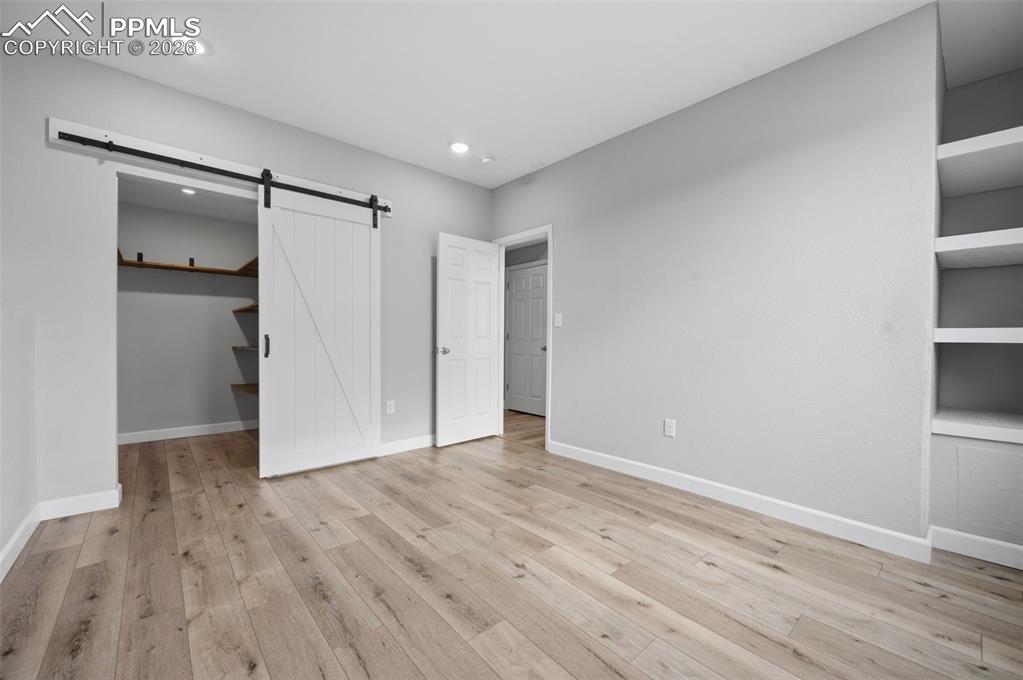 Image 38 of 49: Spacious room featuring wood-finish flooring, a white barn door, recessed l