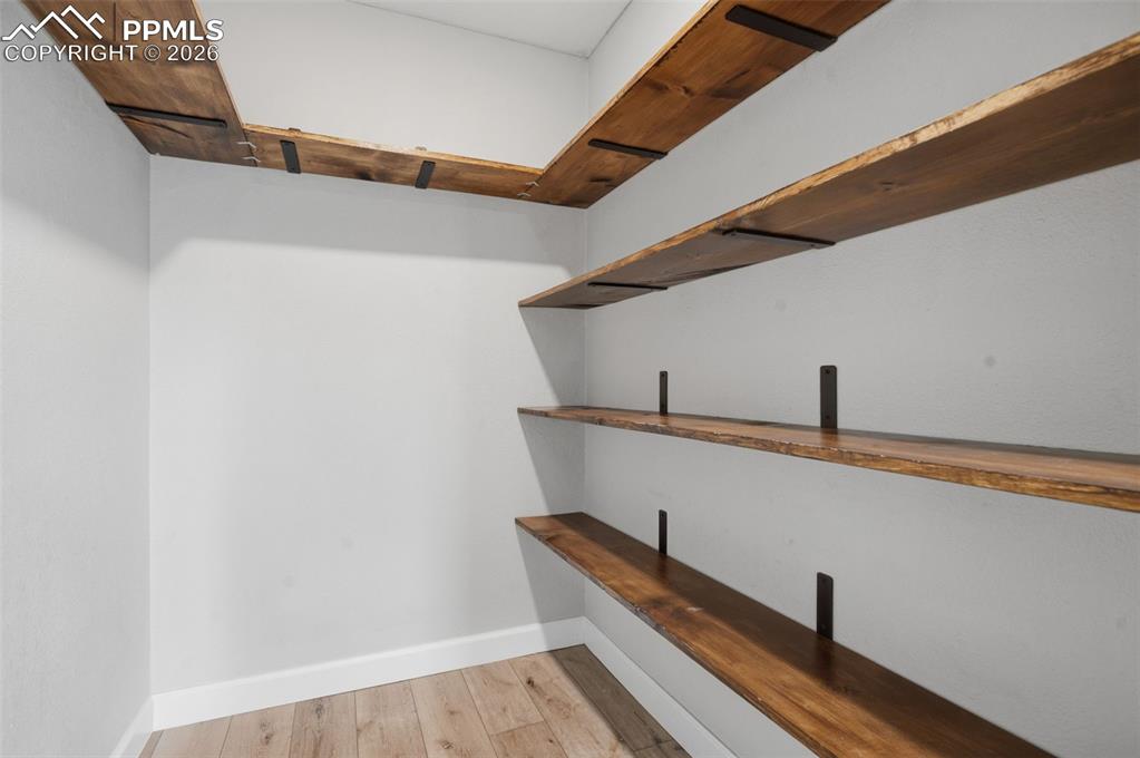 Image 39 of 49: Built-in wood-finish shelving with dark metal brackets, white baseboards, a