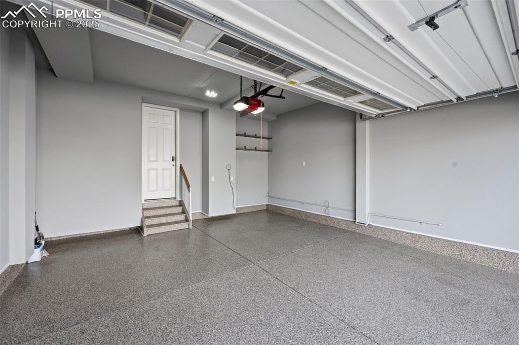 Image 43 of 49: Spacious garage featuring a durable epoxy floor, overhead door, interior ac