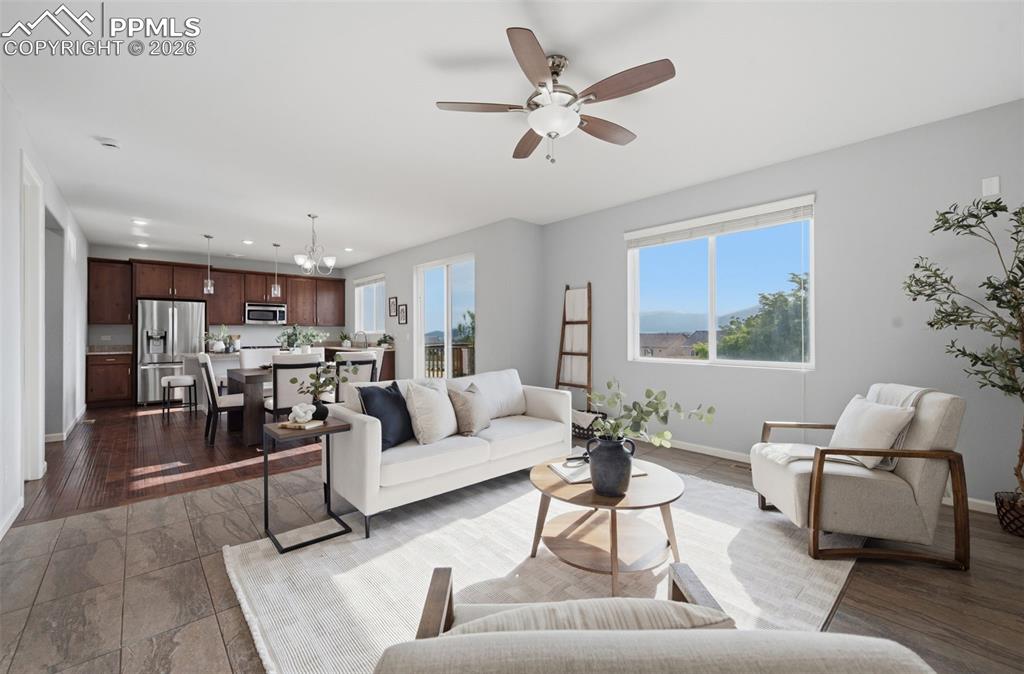 Image 6 of 49: Open-concept living area featuring a ceiling fan, large window, and tile fl