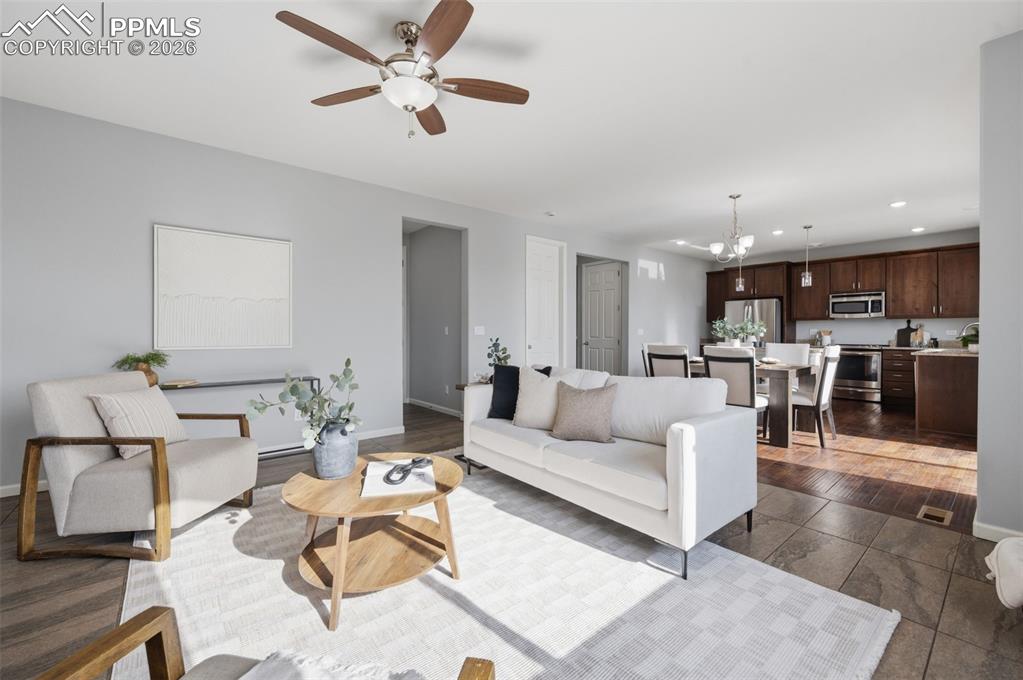 Image 7 of 49: Open-concept living area featuring a ceiling fan, wood-finish flooring, and