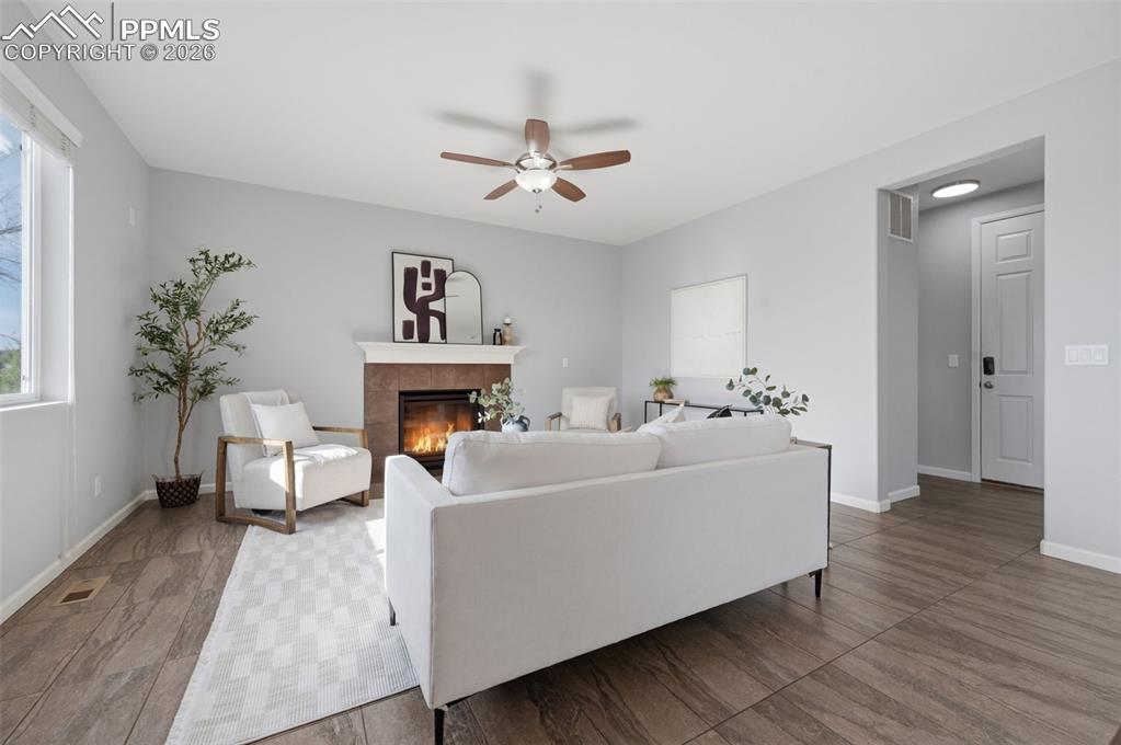 Image 8 of 49: Living area featuring a tile-surround fireplace with a white mantel, wood-f