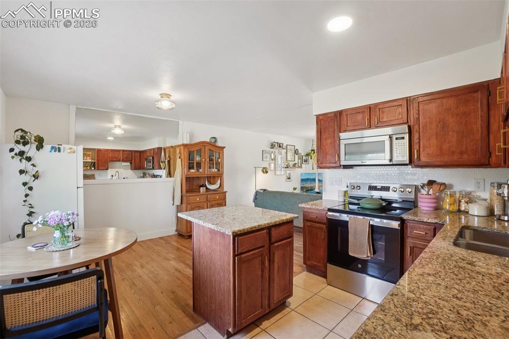 Image 25 of 38: Kitchen with newer appliances, a island and granite countertops 