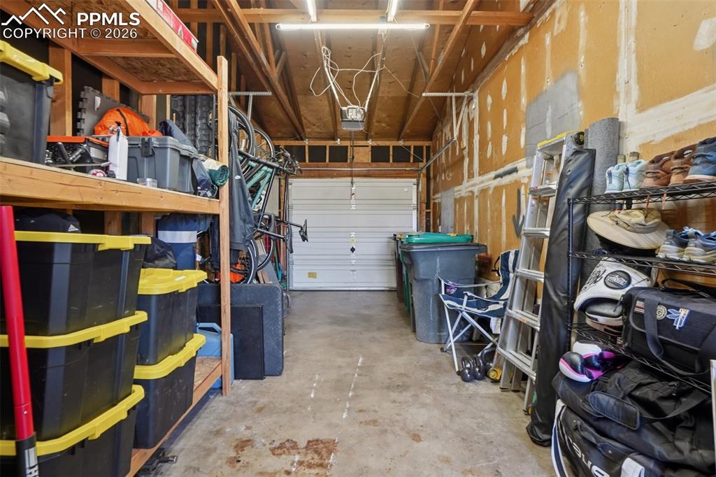 Image 33 of 38: 1 car attached garage with storage racks and a work bench
