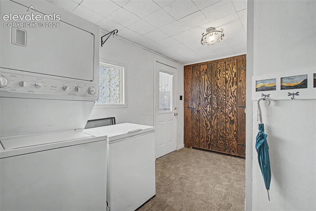 Image 15 of 26: Stacked washer/dryer, small chest freezer, large pantry, entry to yard