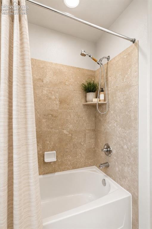 Image 45 of 48: Main Floor Shower White drop-in tub with a tile surround, chrome shower fi
