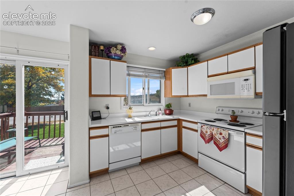 Image 10 of 43: Kitchen featuring white cabinetry with wood-finish trim, white countertop, 