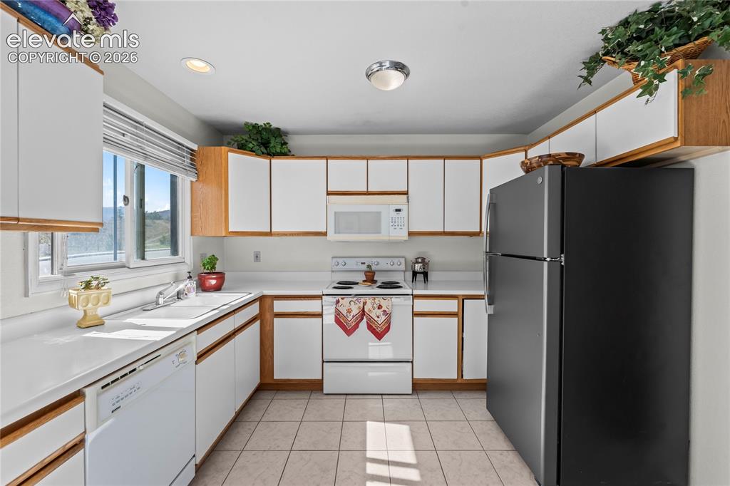 Image 12 of 43: Efficient kitchen featuring white cabinetry with wood-finish trim, white co