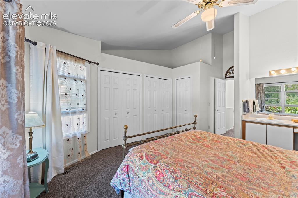 Image 16 of 43: Carpeted bedroom featuring a ceiling fan with integrated lighting, multiple