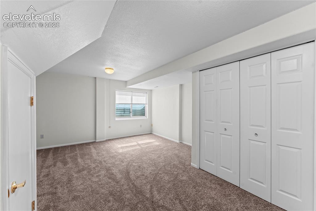Image 24 of 43: Carpeted room featuring a white interior door, a single window, and bi-fold
