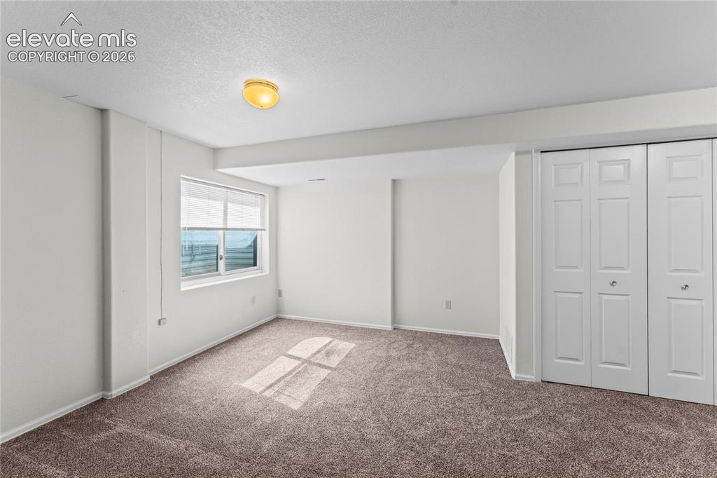 Image 26 of 43: Neutral wall paint throughout, carpeted flooring, window with blinds, and b