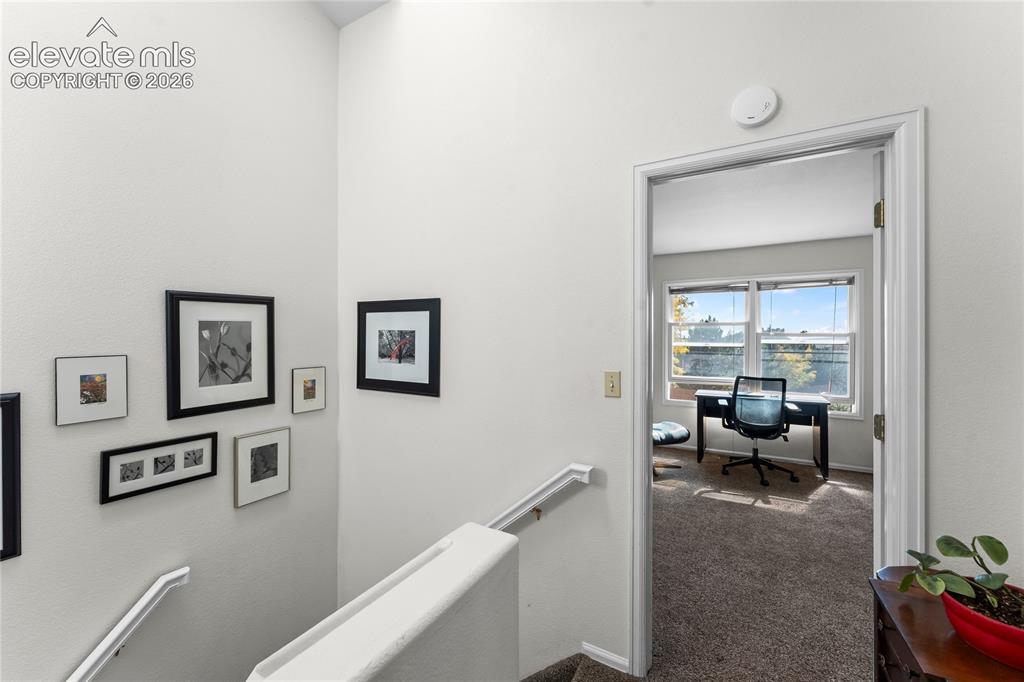 Image 31 of 43: Carpeted upper level with an open doorway leading to a room featuring large