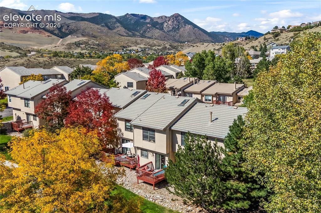 Image 40 of 43: Mountain backdrop with multiple residential structures featuring light-colo