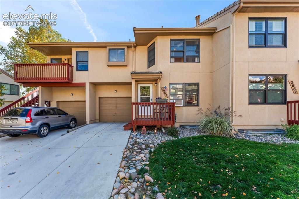 Image 42 of 43: Stucco exterior featuring multiple windows with dark trim, a red-toned wood