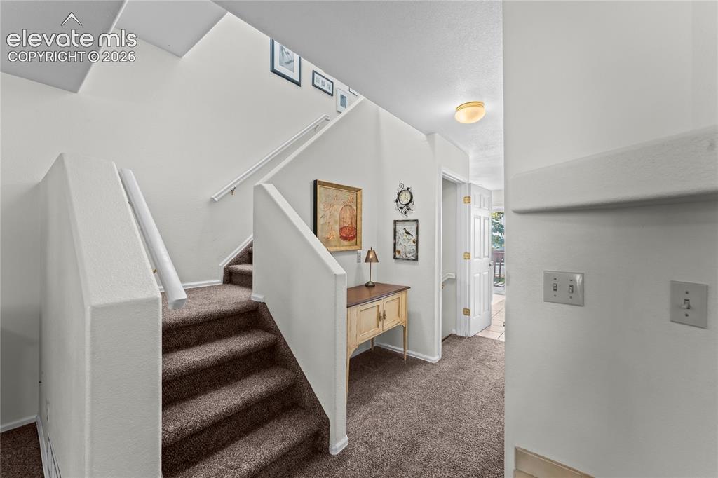 Image 6 of 43: Carpeted staircase with white handrails and wall-mounted light fixture