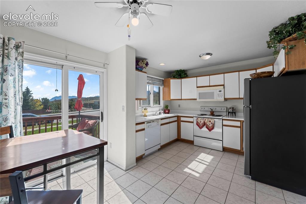 Image 7 of 43: Kitchen featuring L-shaped cabinetry with white doors, tile flooring, and w