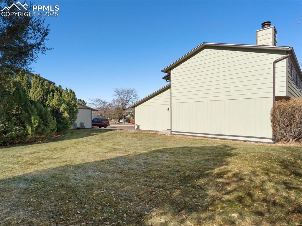 Image 33 of 36: View of side of home with a yard and a chimney