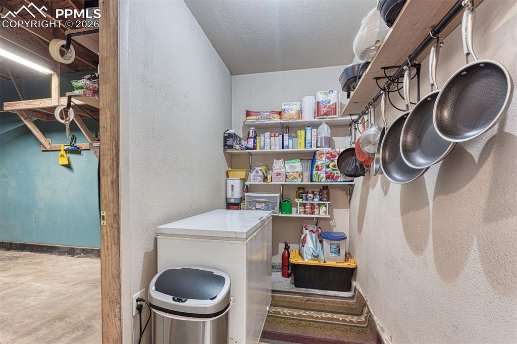 Image 11 of 42: Dedicated pantry space featuring built-in shelving, a freestanding freezer,