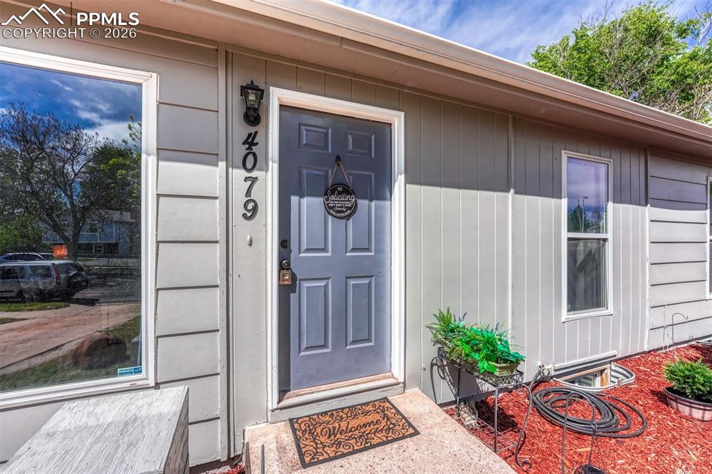 Image 2 of 42: Entryway featuring a paneled door, exterior wall sconce, and house numbers