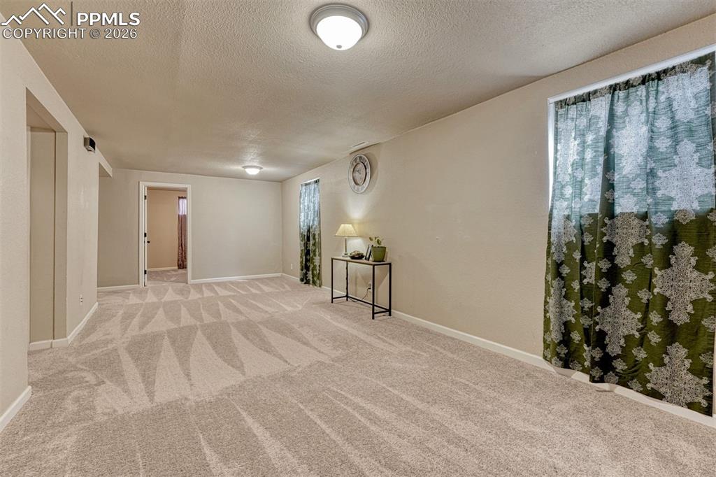 Image 21 of 42: Spacious carpeted room featuring two recessed window openings with curtain 