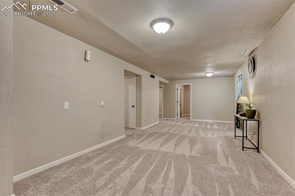 Image 22 of 42: Spacious room featuring patterned carpeting and neutral wall finishes