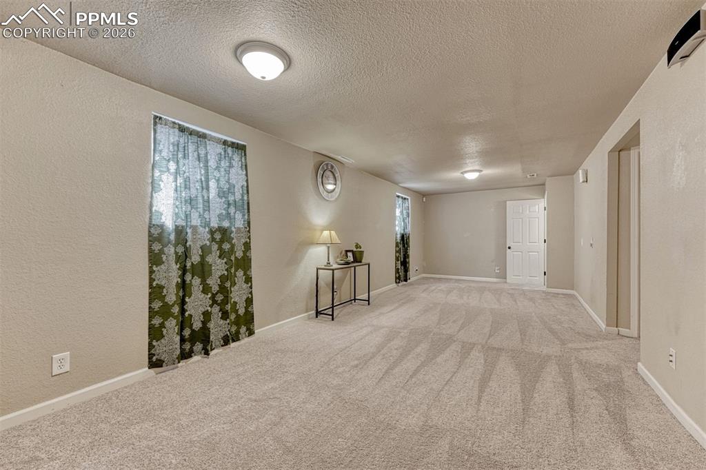 Image 24 of 42: Spacious room featuring light-toned carpeting, neutral wall paint, and mult