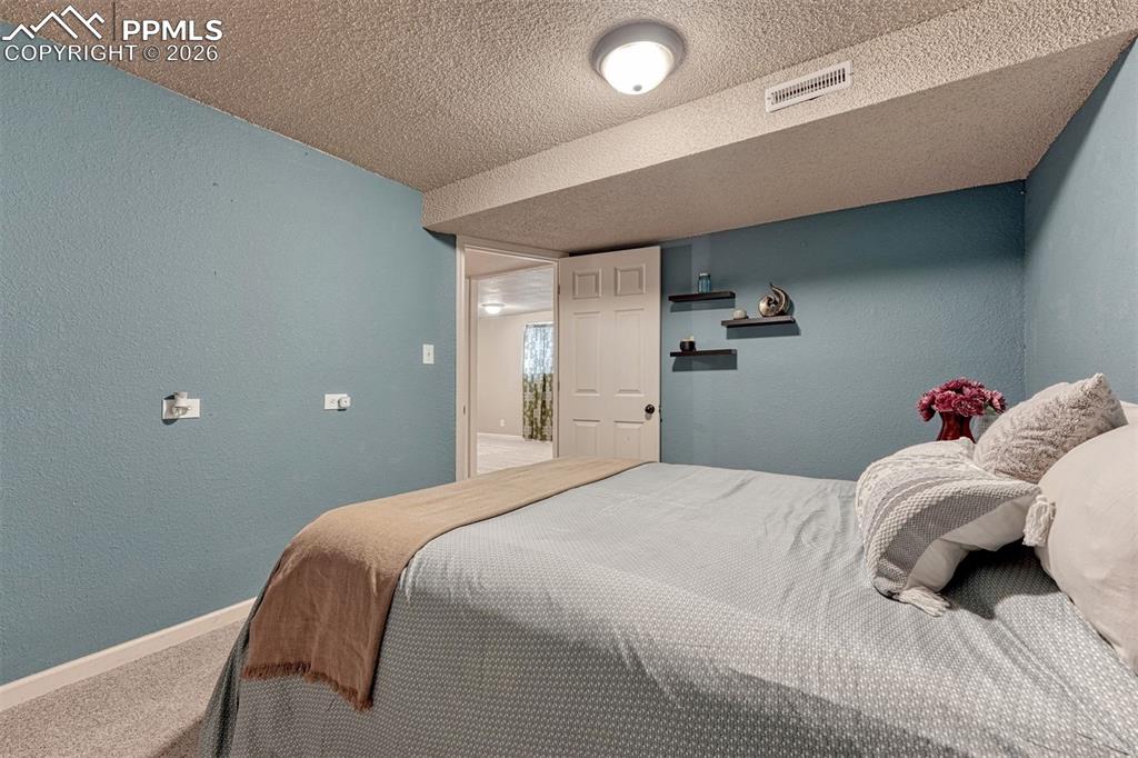 Image 27 of 42: Bedroom featuring light blue walls, textured ceiling, and neutral-toned car