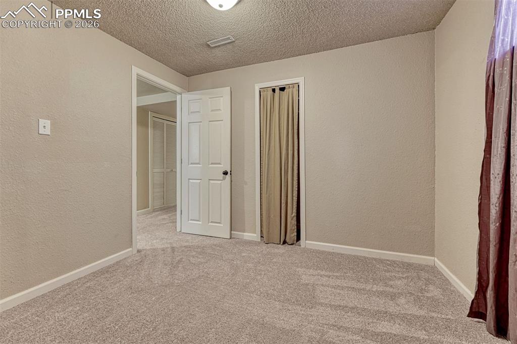 Image 28 of 42: Neutral-toned room featuring light textured walls and a matching carpeted f