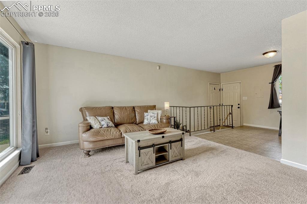 Image 3 of 42: Spacious living area featuring neutral carpeting, a large picture window, a