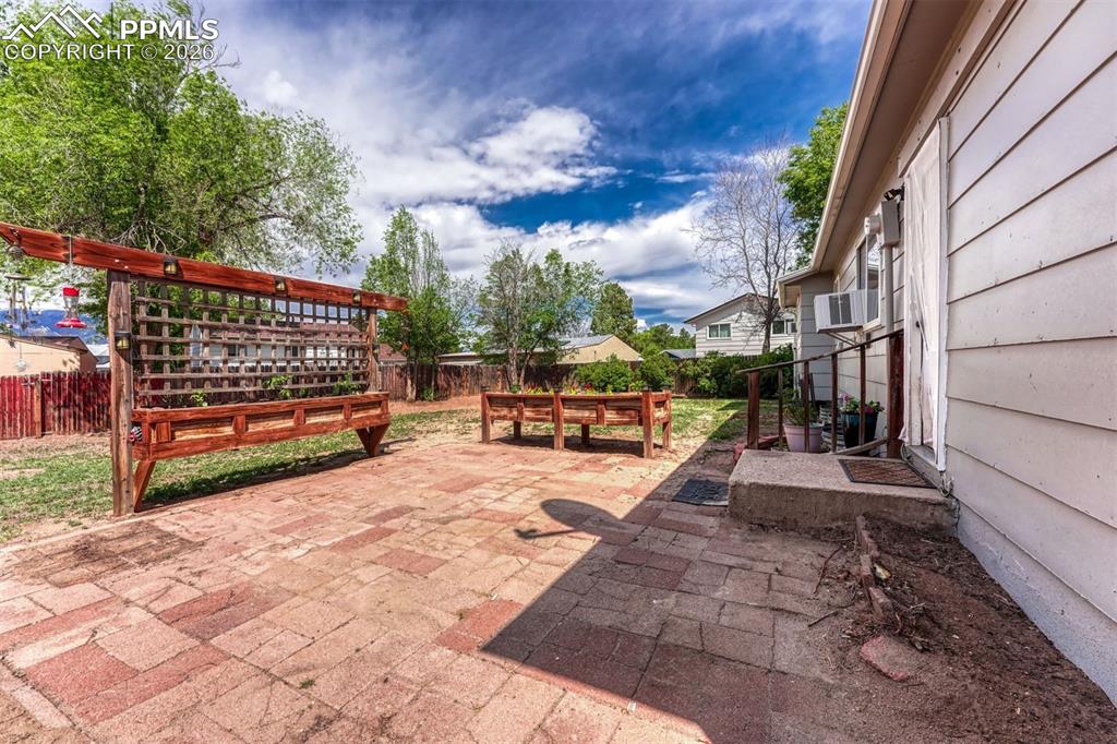 Image 33 of 42: Spacious backyard featuring a brick paver patio, a large wooden trellis, an