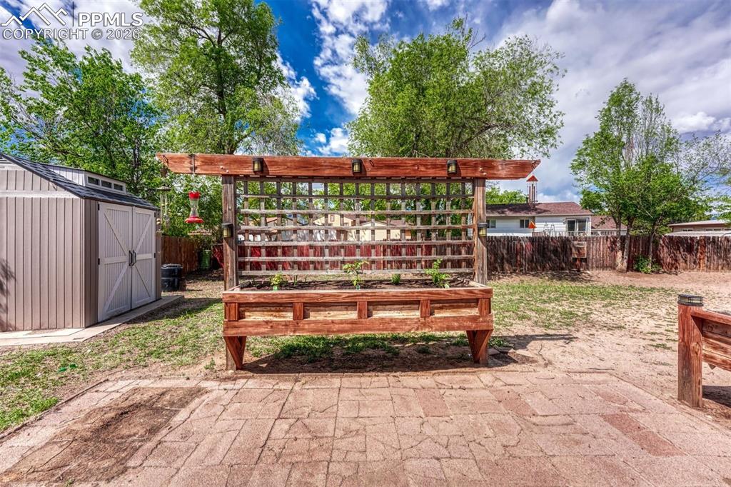 Image 35 of 42: Backyard featuring a red-toned wood planter box with integrated trellis, a 