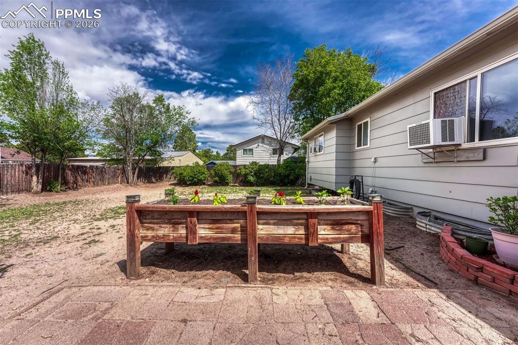 Image 38 of 42: Backyard featuring a raised wooden planter box, a brick paver patio, wood f