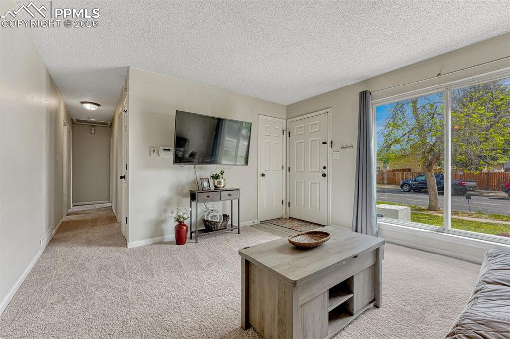 Image 4 of 42: Living area featuring light-toned carpet flooring and a large picture windo