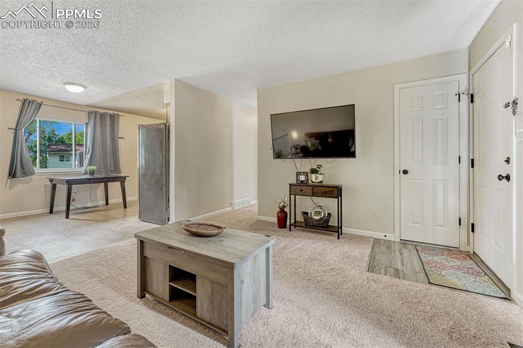 Image 6 of 42: Open concept living space featuring neutral carpeting, a window providing n