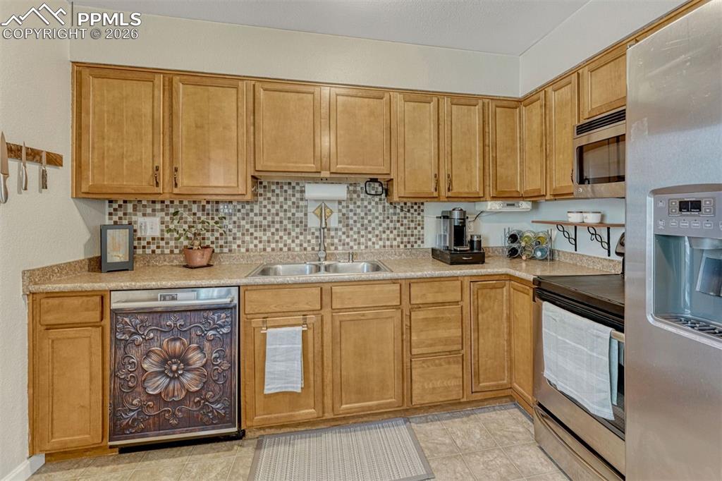 Image 8 of 42: Kitchen featuring light wood cabinetry, a mosaic tile backsplash, double ba
